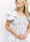 Close up of tiered ruffle short sleeve, v-neck and smocked bodice on a white maxi with blue floral. 