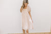 Model wearing a blush dress with a rayon material, ruffle detail and short sleeves.