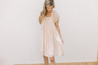 Model wearing a blush dress with a rayon material, ruffle detail and short sleeves.