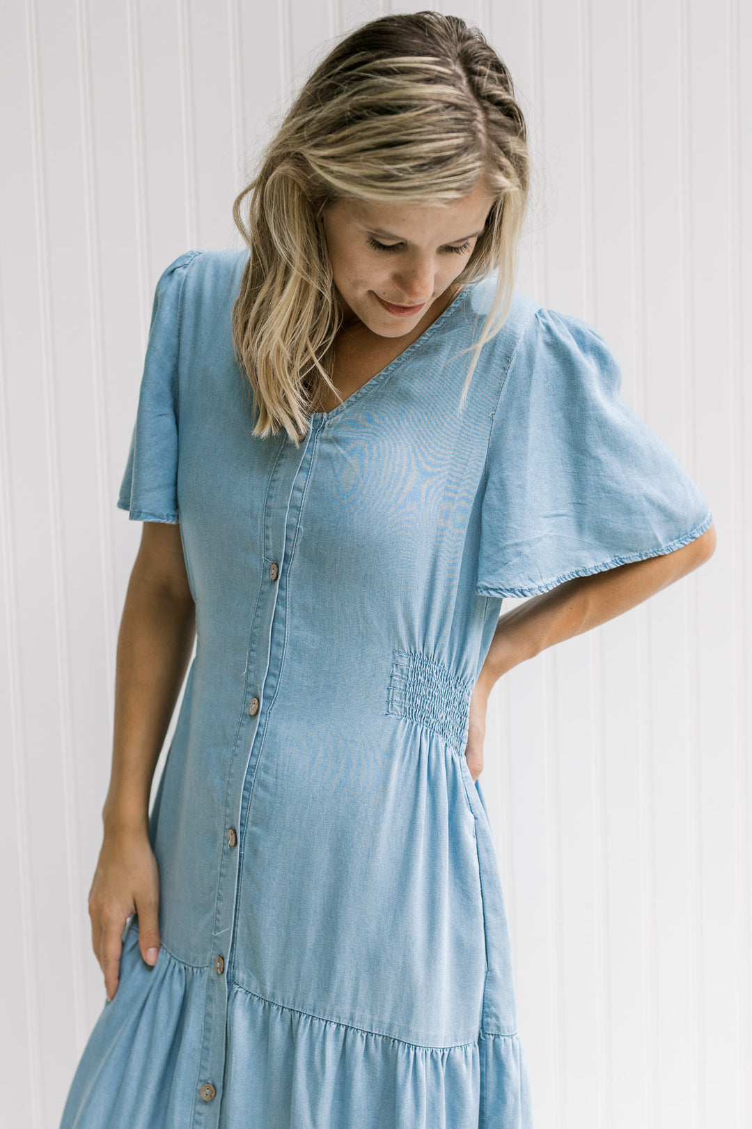 Model waring a v-neck chambray midi with smocked side detail and flutter short sleeves.
