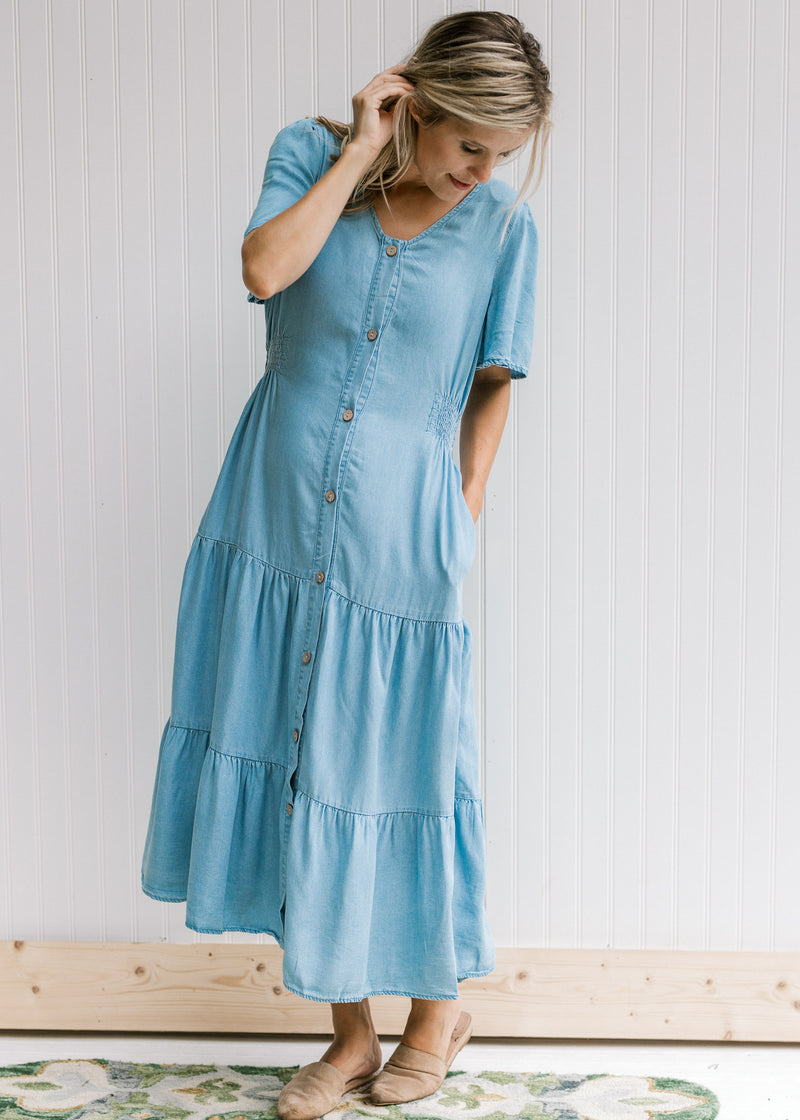 Model wearing a button up midi with a light chambray color and short sleeves.