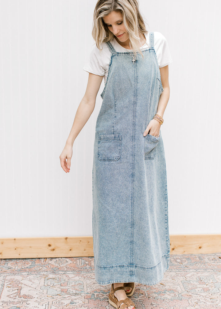 Model wearing a light denim midi with front pouch pockets, side zipper and a rounded back detail. 