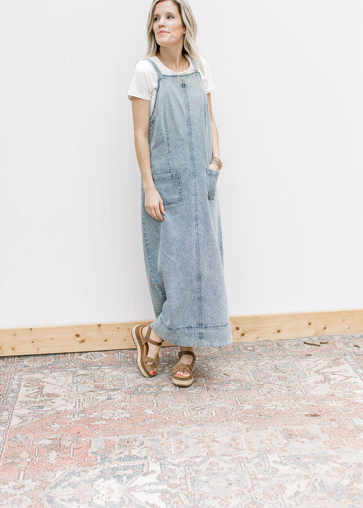 Model wearing sandals and a light denim midi with pouch pockets, side zipper and a rounded back. 