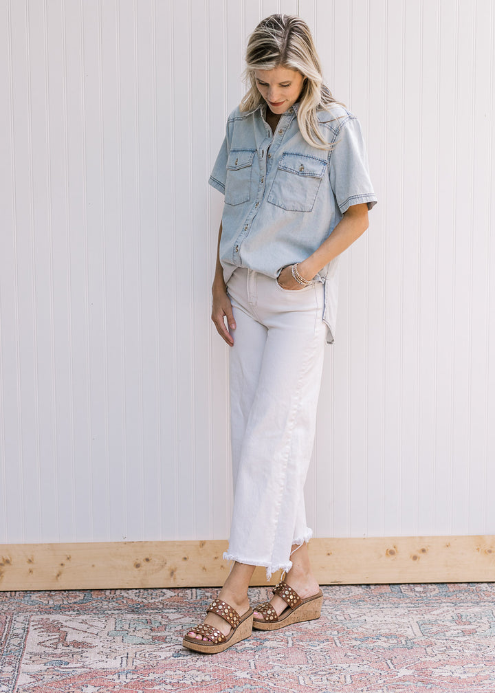 Model wearing heels, white denim and a short sleeve, button up chambray top with a collar. 