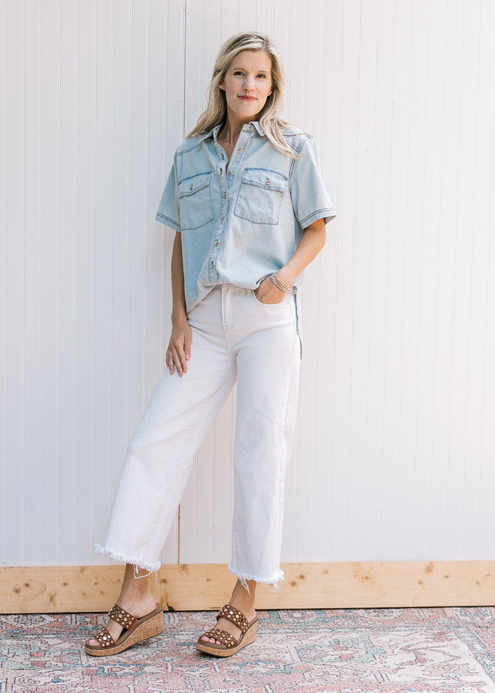 Model wearing white jeans and a button up chambray top with short sleeves and patch pockets. 