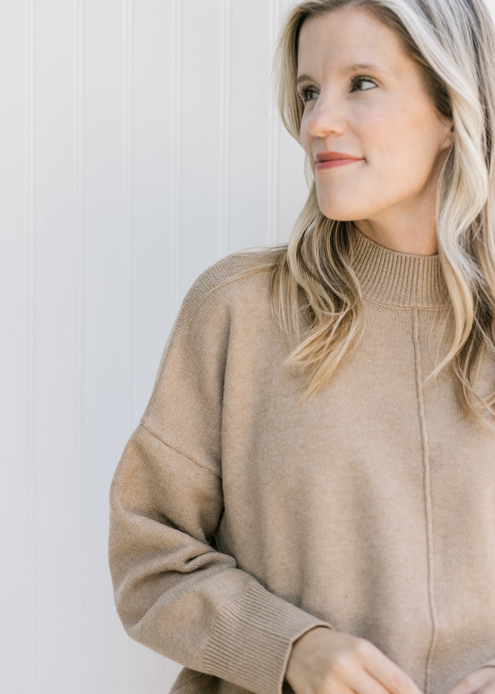 Close up of mock neck with ribbed detail on a camel long sleeve sweater with seam down middle.