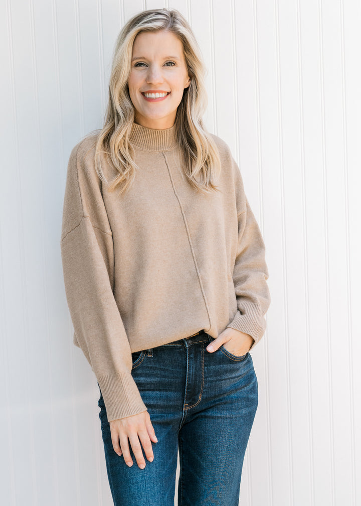 Model wearing a camel knit sweater with extended shoulder detail, mock neck and long sleeves.