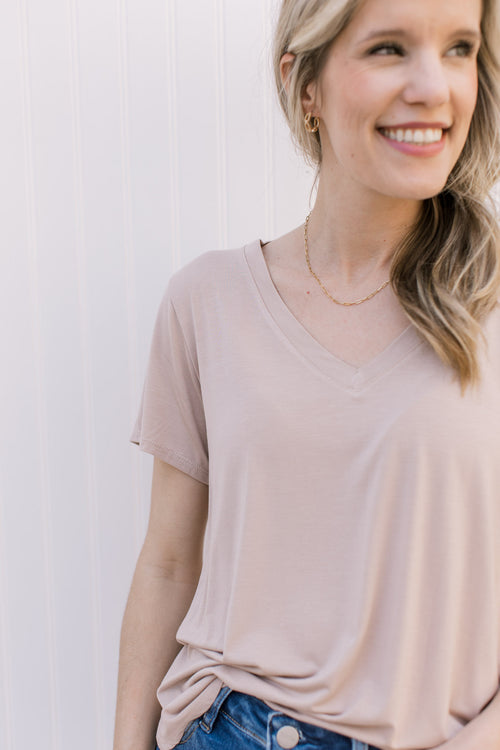 Model wearing a light taupe short sleeve top with a v-neck and rayon/spandex blend.
