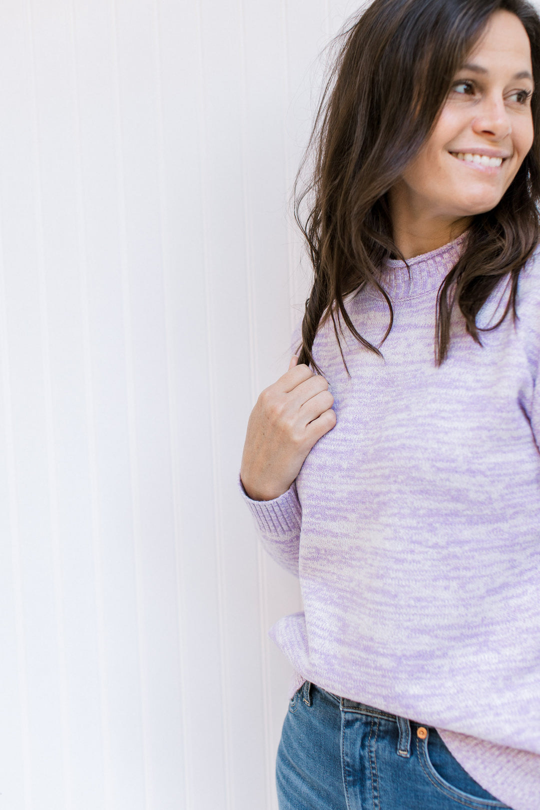 Model wearing a lilac long sleeve sweater with a mock neckline and a ribbed cuff and hem. 