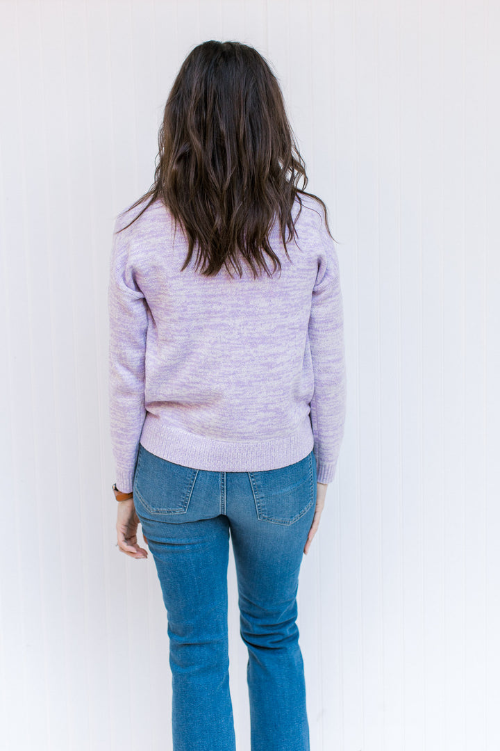 Back view of Model wearing a lilac long sleeve sweater with a mock neck and a ribbed cuff and hem. 