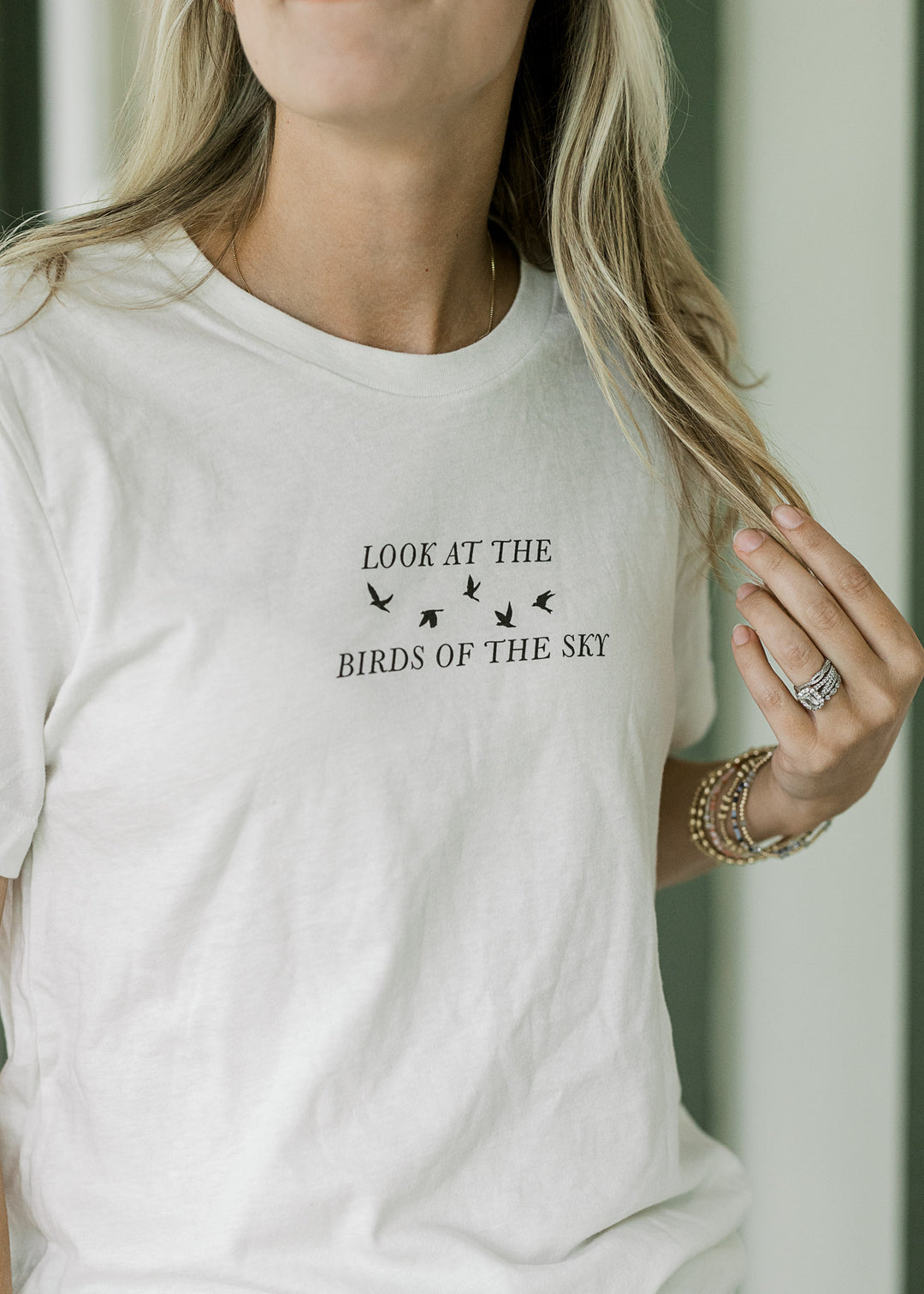 Model wearing a cream tee with a crew neck and black look at the birds of the sky graphic.