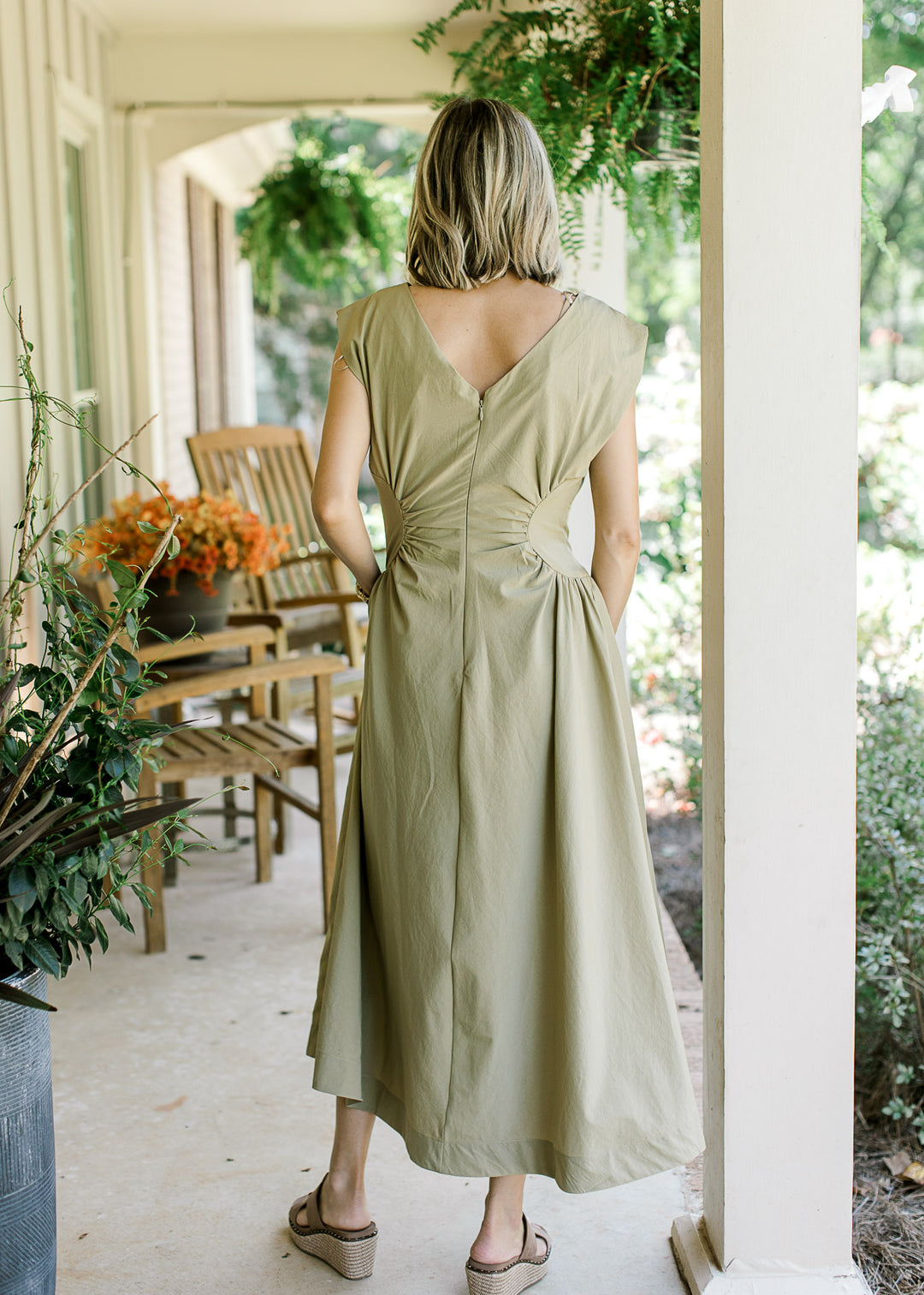 Back view of Model wearing a mossy tan sleeveless maxi with hidden back zipper and pockets. 