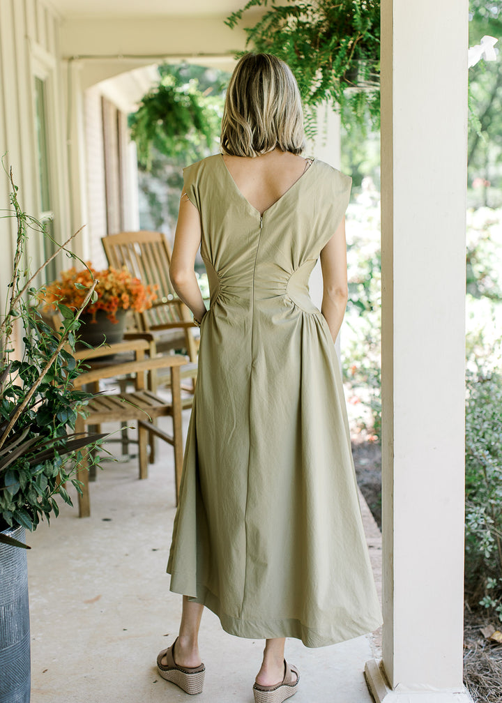 Back view of Model wearing a mossy tan sleeveless maxi with hidden back zipper and pockets. 