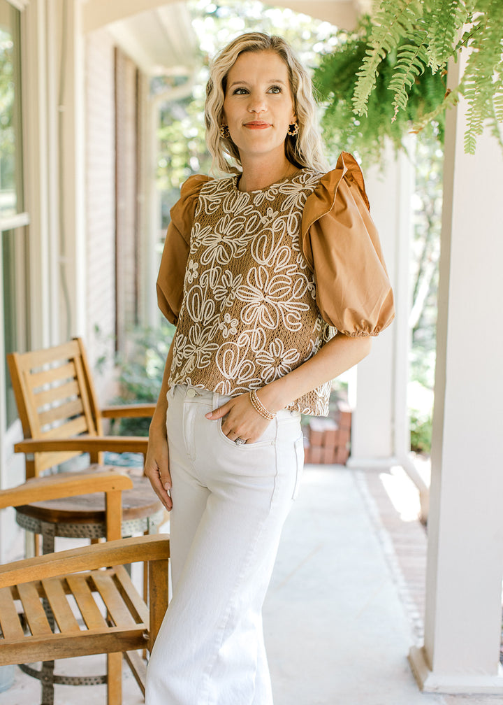 Model wearing a camel top with white embroidered flowers and short puff sleeves 
