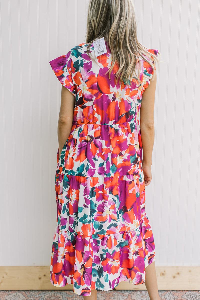 Back view of Model wearing a white dress with magenta flowers, ruffle cap sleeve, and elastic waist.