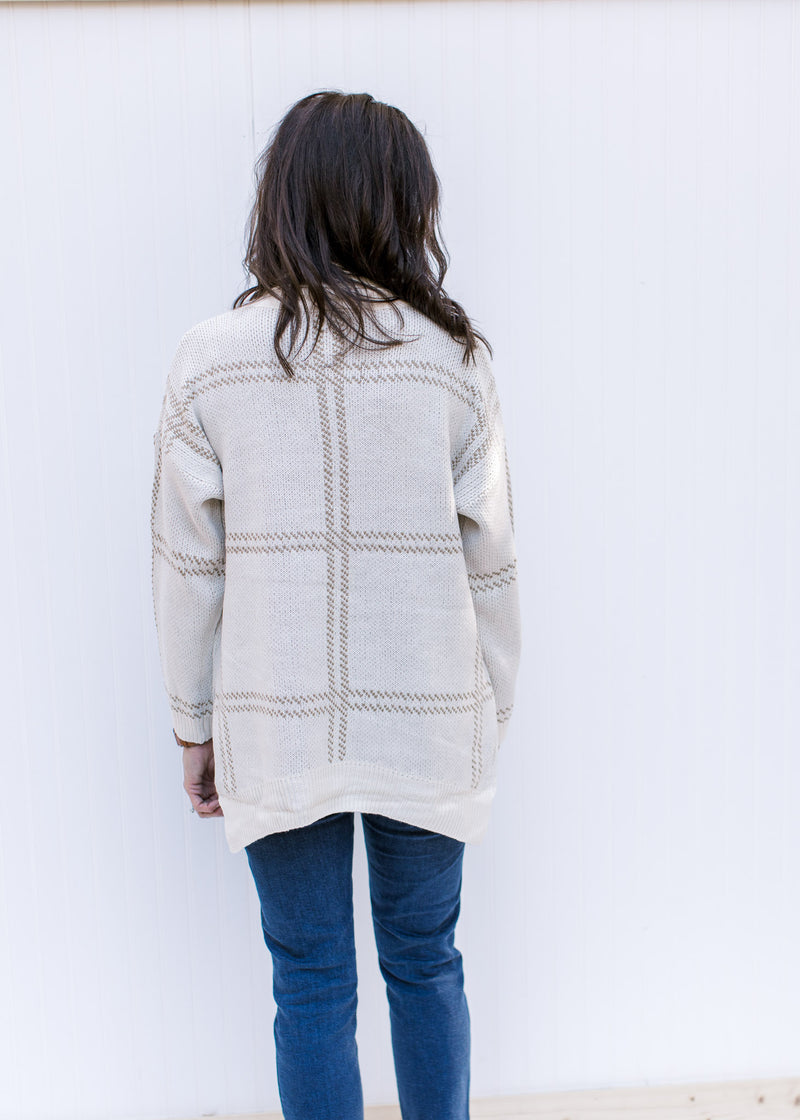 Back view of Model wearing a camel on cream plaid sweater with a turtleneck and long sleeves.