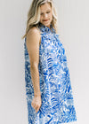 Model wearing a white sleeveless button up dress with a blue animal and tree print and a collar.