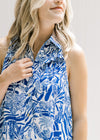 Close up view of ruched detail and ruffle on bust of a blue and white button up dress. 