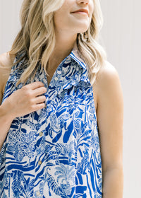 Close up view of ruched detail and ruffle on bust of a blue and white button up dress. 
