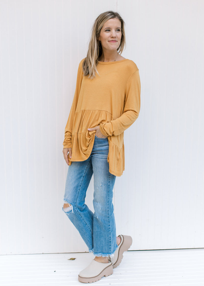Model wearing jeans, mules and a marigold bamboo top with tiers and long sleeves. 