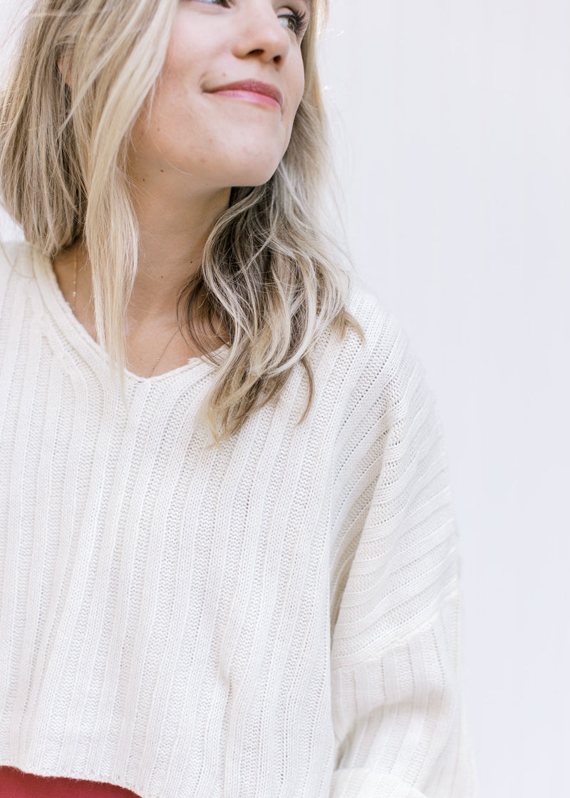 Close up of an ivory v-neck crop sweater over a soft maroon colored maxi. 