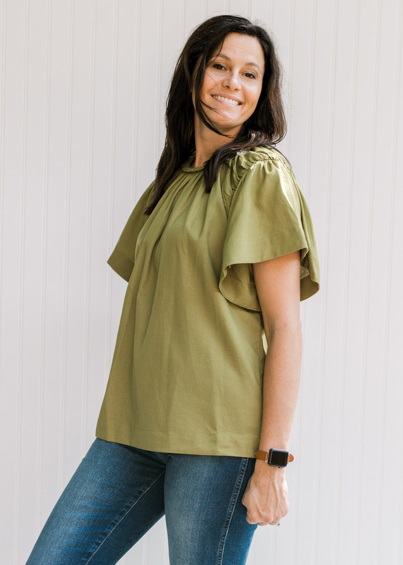 Model wearing an olive top with a braided neck detail, batwing short sleeves and a round neck.