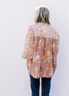 Back view of Model wearing a mauve mixed floral top with sheer long bubble sleeves.