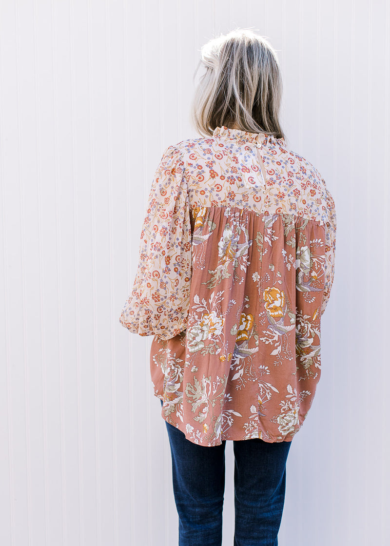 Back view of Model wearing a mauve mixed floral top with sheer long bubble sleeves.