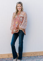 Model wearing jeans, booties and a mauve mixed floral top with sheer long bubble sleeves. 