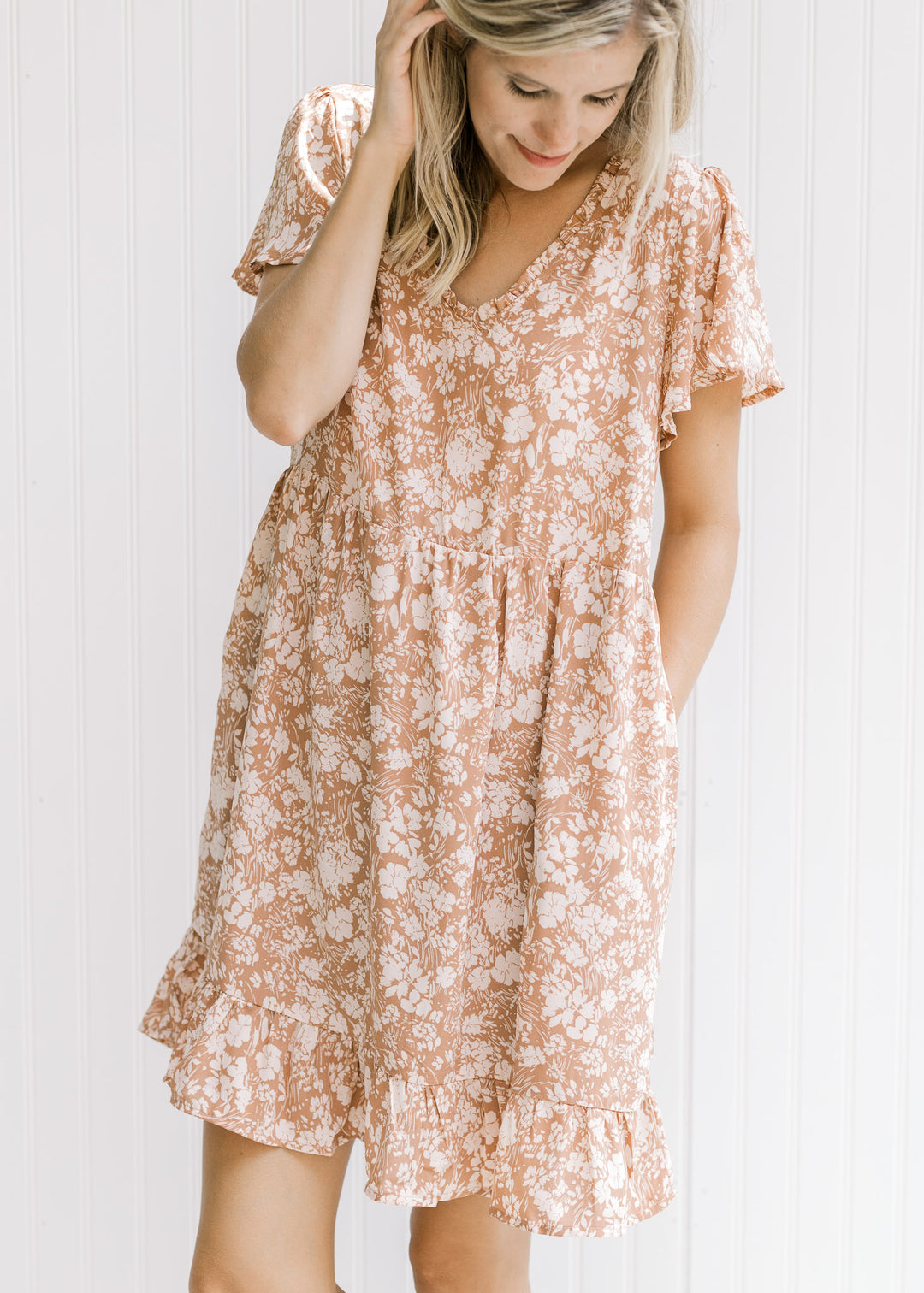 Model wearing a mauve dress with a cream floral, v-neck with ruffle and flutter short sleeve.