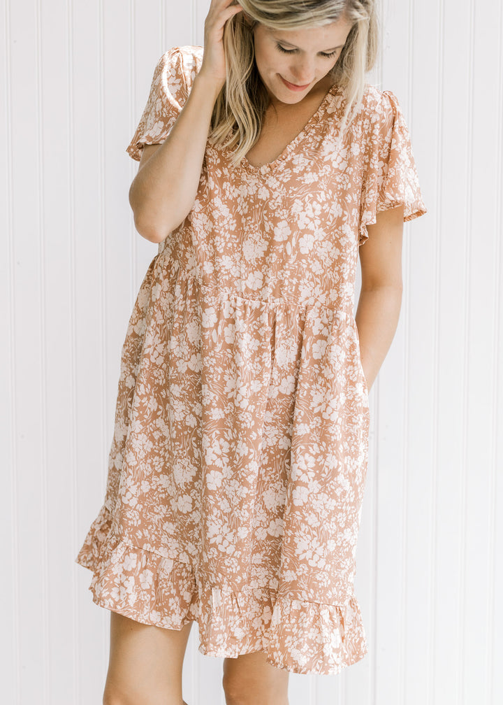 Model wearing a mauve dress with a cream floral, v-neck with ruffle and flutter short sleeve.
