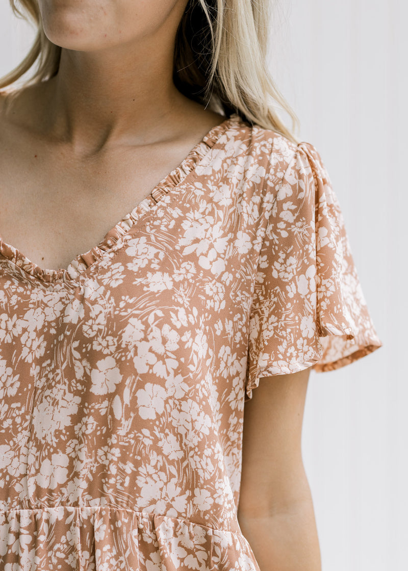 Close up of a v-neck with a ruffle and flutter short sleeves on a mauve dress with cream floral. 