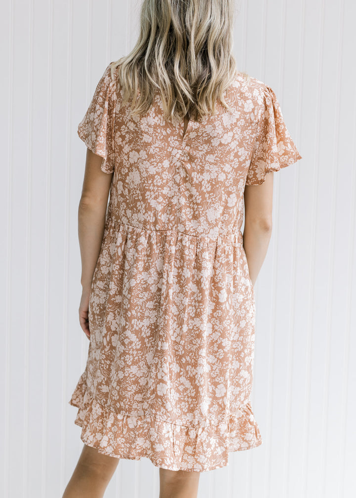 Back view of Model wearing a mauve above the knee dress with a cream floral and flutter short sleeve