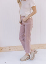 Model wearing a white top, mules and mauve mid rise jeans with a cropped fit.