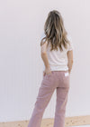 Back view of Model wearing mauve mid rise jeans with a cropped fit and button/zip closure.