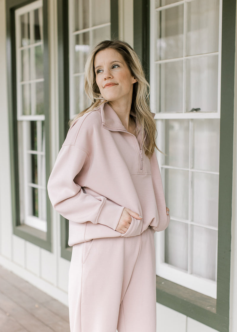 Model wearing a mauve quarter zip long sleeve top with matching joggers with elastic waist. 