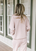 Back view of Model wearing a mauve long sleeve top and matching joggers with elastic waist. 