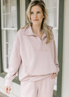 Model wearing a mauve quarter zip top with long sleeves and a front pouch pocket. 