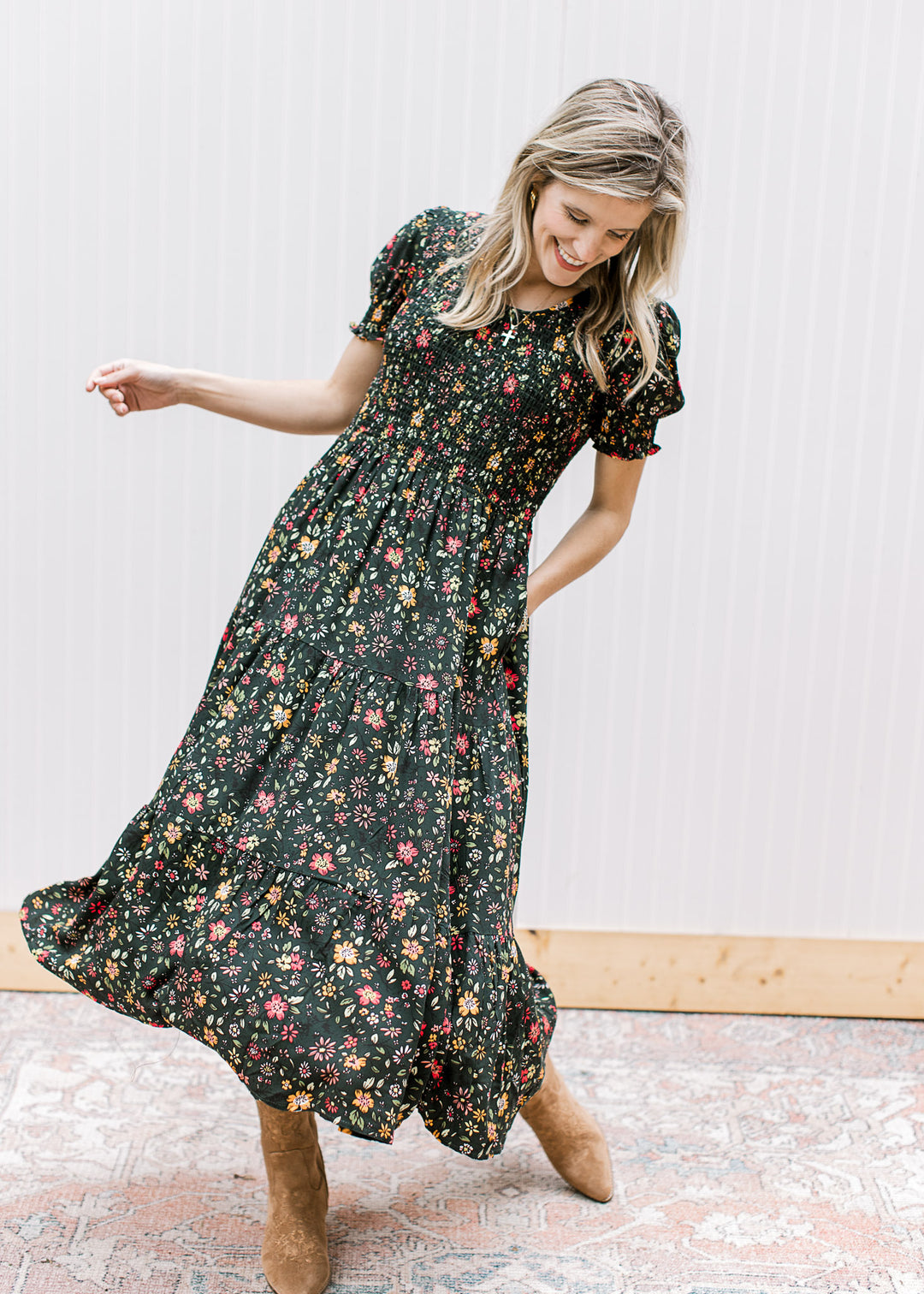 Model twirling in a hunter green midi with warm floral, smocked bodice, and bubble short sleeves.