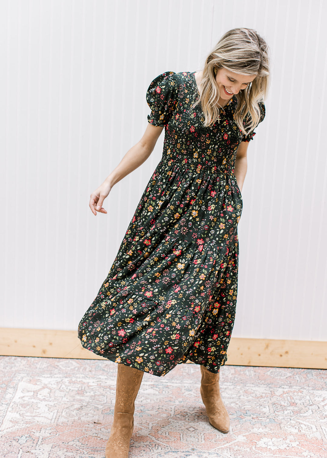 Model wearing a hunter green midi with warm floral, smocked bodice, pockets and short sleeves.