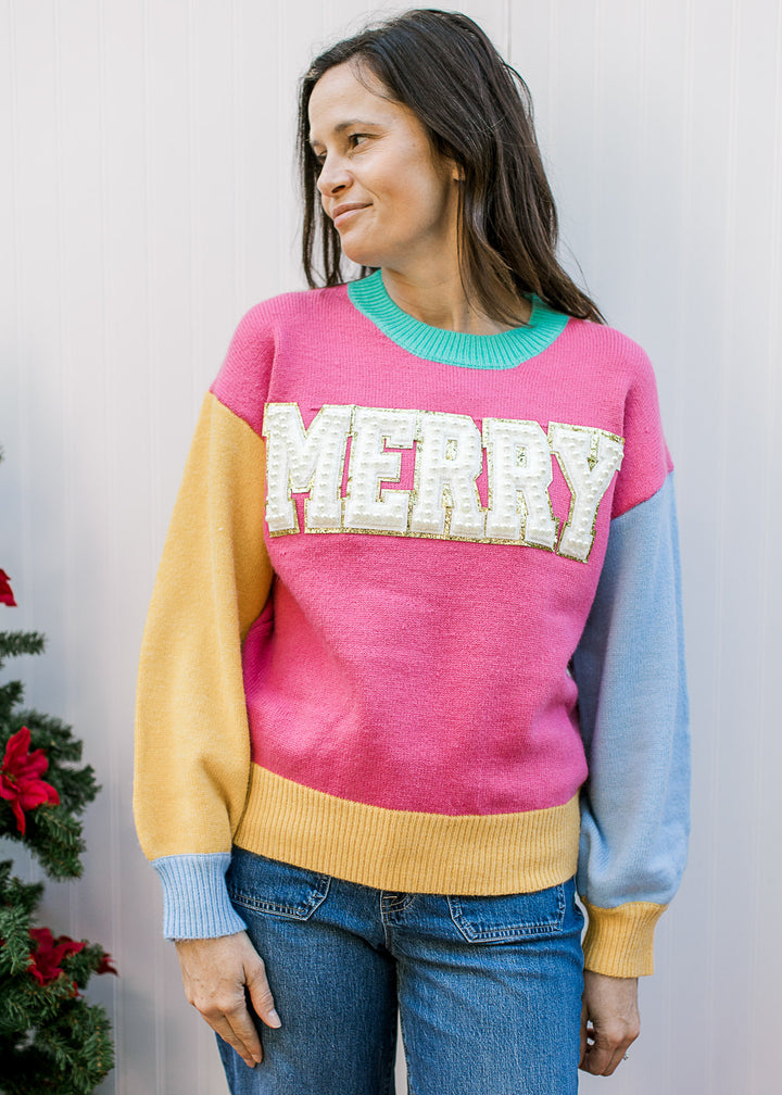 Model wearing a bright colorblock  “MERRY” sweater with a round neckline and long sleeves. 