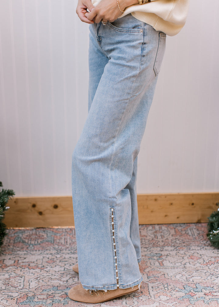 Side view of Mica Denim mid-rise wide leg jeans in light wash with pearl-trimmed side slit and frayed hem.