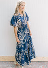 Model wearing wedges with a navy maxi with cream floral, smocked waist and puff short sleeves.