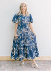 Model wearing a navy maxi with cream floral, smocked waist and puff short sleeves.