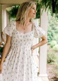 Close up of sweetheart neck, smocked waist and bubble short sleeves on a cream maxi with floral.