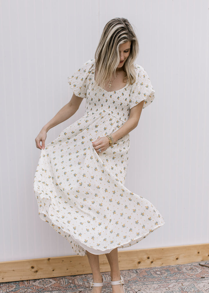 Model twirling a cream maxi with yellow floral, smocked bodice, v-neck and bubble short sleeves. 