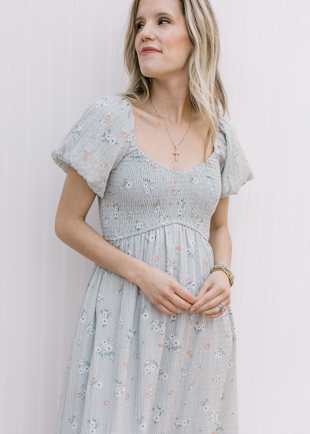 Model wearing a baby blue maxi with peach and cream floral print and a smocked bodice. 