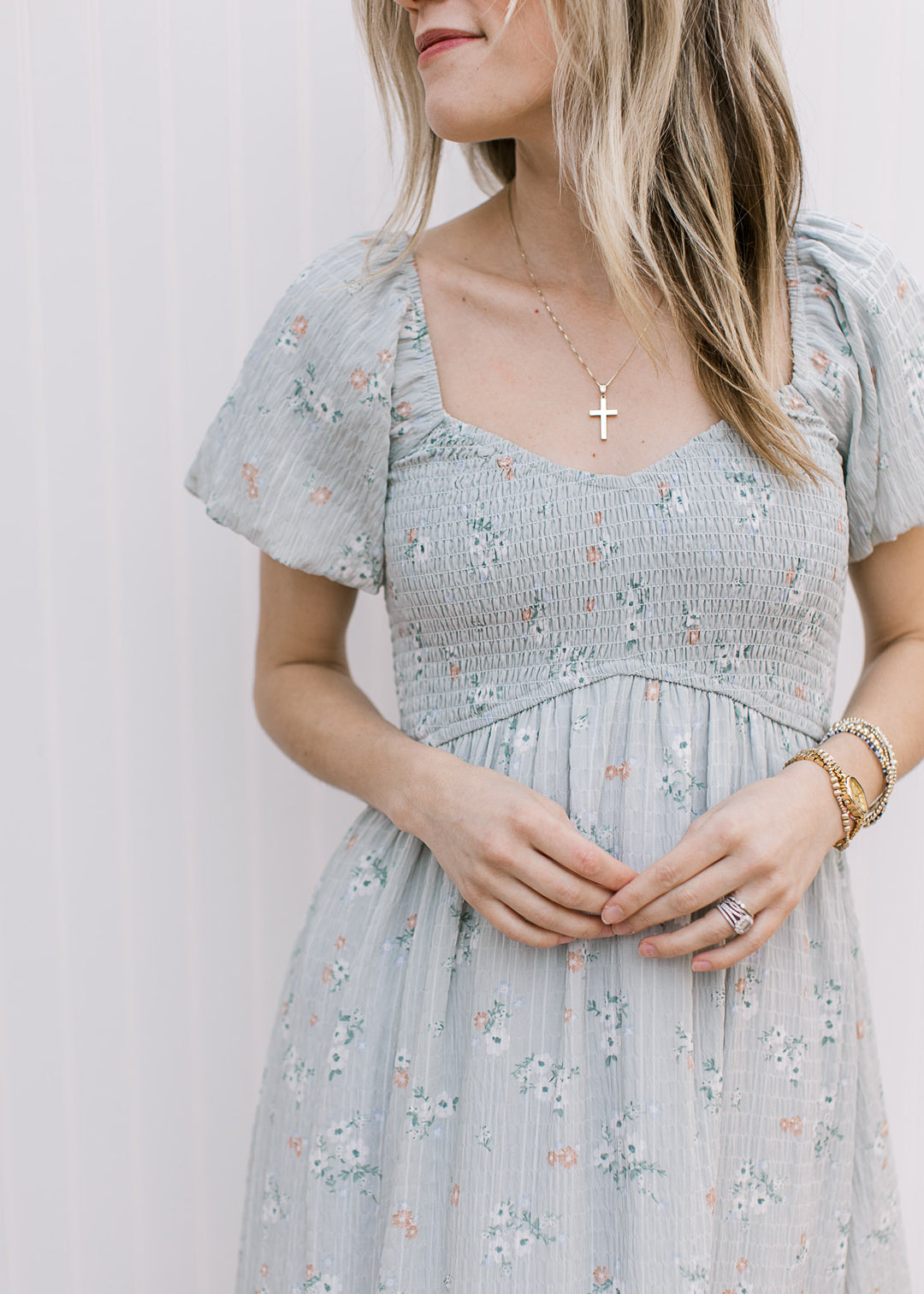 Close up of v-neck, bubble short sleeves and smocked bodice on a pale blue maxi with floral.