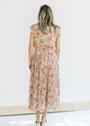 Back view of Model wearing a mint dress with a salmon, taupe and cream floral pattern. 