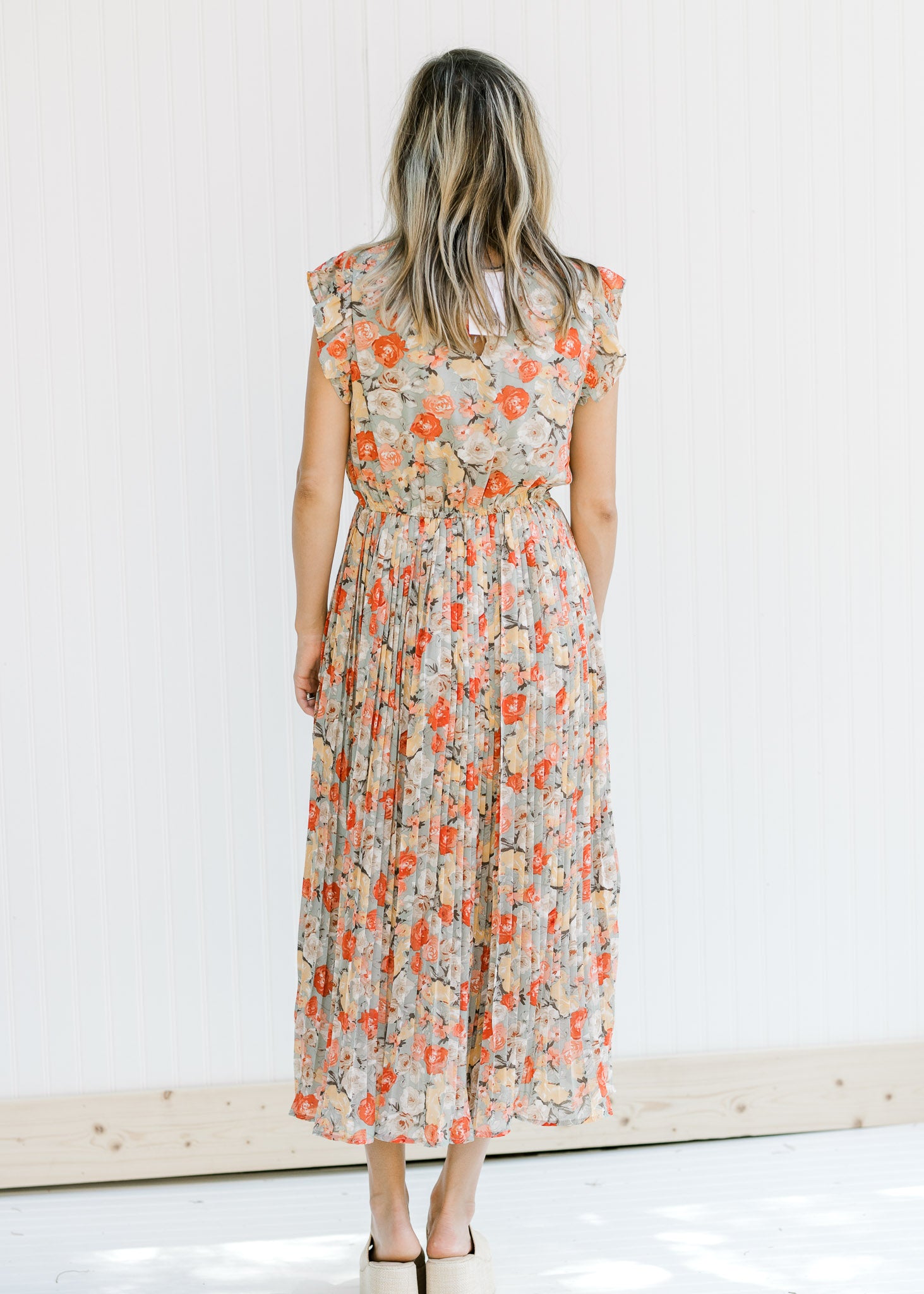 Back view of Model wearing a mint dress with a salmon, taupe and cream floral pattern. 
